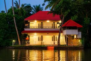 a house with a red roof on the water at Chilanka Lake View Resort in Alleppey