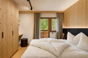 a bedroom with a large white bed and a window at Ciasa Col Cuch in La Villa