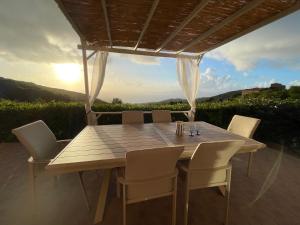 a wooden table and chairs with the sunset in the background at Charmante Maison Vue mer Panoramique à Coti-Chiavari in Coti-Chiavari