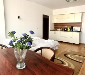 een vaas met blauwe bloemen op een houten tafel bij ApartHotel Zorilor in Cluj-Napoca