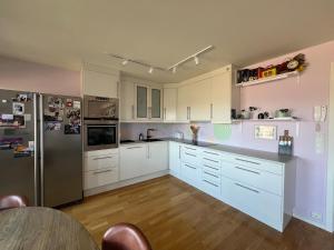 a kitchen with white cabinets and a stainless steel refrigerator at Spacious apartment with amazing views in Sandnes