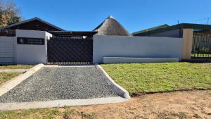a house with a fence and a yard with grass at Bootleg Inn in Welkom