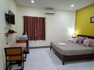 a bedroom with a bed and a chair and a window at สายป่าน เฮ้าส์ แพร่ in Ban San Pa Yae