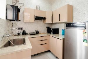 a kitchen with white cabinets and a stainless steel refrigerator at HomeGround Sector 89 -1RK in Gurgaon