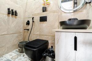 a bathroom with a black toilet and a sink at HomeGround Sector 89 -1RK in Gurgaon +15 photos