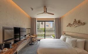a hotel room with a bed and a television at Riva Hua Hin in Ban Khao Takiap