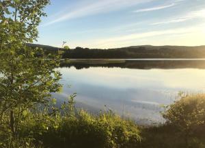 a view of a lake with the sun setting at Lakeside Guesthouse, Lillstugan in Ramvik