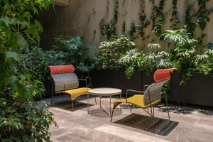 three chairs and a table in a garden at Nomu Mexico City by Lumina in Mexico City