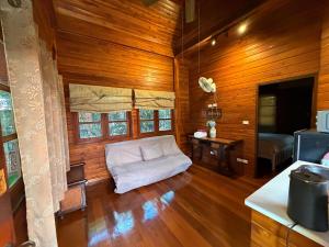 a living room with wooden walls and a white couch at Golden Teak Resort Baan Sapparot in Kamala Beach