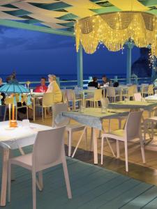 a restaurant on the beach with tables and chairs at Oldwell Hotel in Santa Domenica