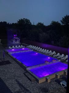 a swimming pool with chairs and purple lights at Готель Соняшник in Solotvyno