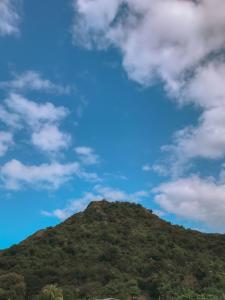 a mountain under a blue sky with clouds at Anorawi surf accommodation in Maluk