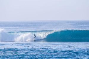 a person riding a wave on a surfboard in the ocean at Anorawi surf accommodation in Maluk