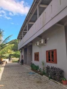 a white building with some plants in front of it at Anorawi surf accommodation in Maluk
