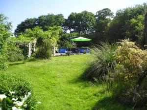 - un jardin avec une table et un parasol vert dans l'établissement Peach Cottage, à La Forêt-sur-Sèvre