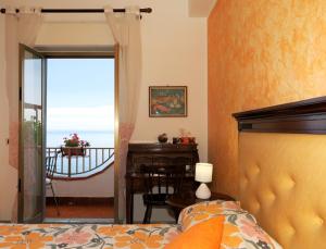 a bedroom with a bed and a table and a window at Camere Santa Margherita in Santa Margherita-Sant'Alessio Siculo