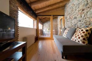 a living room with a couch and a stone wall at Ca l'Espavil in Cardedeu