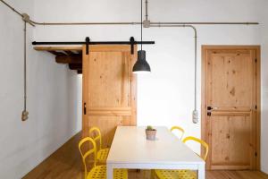 a dining room with a white table and yellow chairs at Ca l'Espavil in Cardedeu