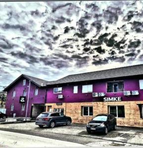 two cars parked in front of a purple building at Prenociste Simke 2 in Subotica