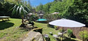Ein weißer Sonnenschirm und Stühle in einem Garten mit Pool in der Unterkunft Stalla in Ortiporio