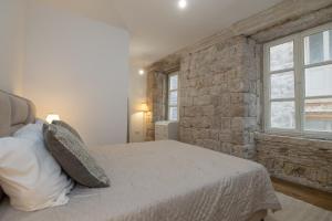 a bedroom with a bed and a brick wall at Dubrovnik Deluxe Rooms in Dubrovnik