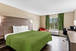 a hotel room with a large bed with a green blanket at Econo Lodge Willowbrook in Burr Ridge
