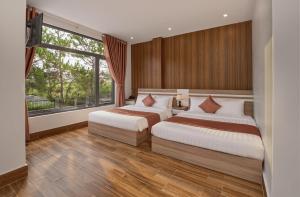 a bedroom with two beds and a large window at Luxury Hotel Dalat in Xuan An