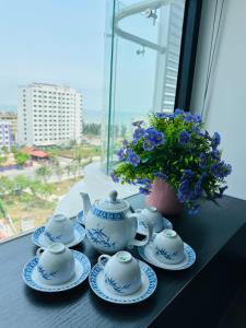 a table with blue and white tea sets and a vase with flowers at Khách sạn LAzur Cửa Lò- Nghệ An in Giáp Vinh Yên