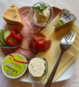 a plate of food with meats and cheese and utensils at Haus Bodenwinkler in Gröbming