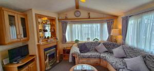 a small living room with a couch and a television at MOLLIES DEN 2 8 Berth 3 Bedrooms The Grange Holiday Park INGOLDMELLS in Ingoldmells