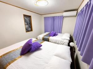 two beds in a room with purple curtains at HORIKIRI House TOKYO in Tokyo