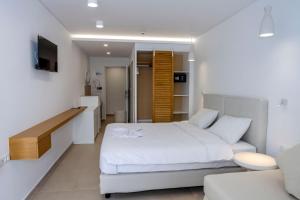 a white bedroom with a bed and a couch at Plaza Hotel in Masouri