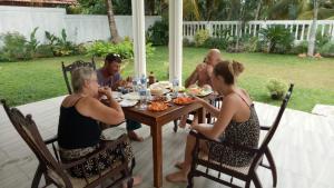 a group of people sitting around a table eating food at Hill House Rest in Mirissa