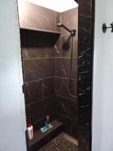 a bathroom with a shower with a black tiled wall at Au petit bonheur chez l'habitant in Ferques +7 photos