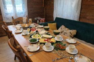 a wooden table with plates and cups on it at Agroturystyka Ranczo u Oli in Krynki Białokunki