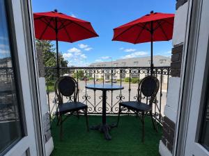 a patio with two chairs and a table and two umbrellas at Le Balcon in Montargis