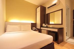 a bedroom with a bed and a desk with a mirror at The V Hotel in Kuantan