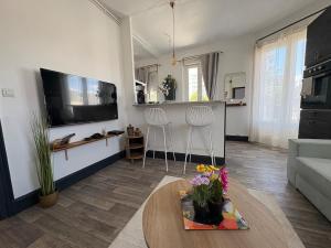 a living room with a table and a tv at Le Balcon in Montargis