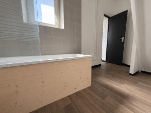 a bathroom with a bath tub and a wooden floor at Le Balcon in Montargis +2 photos