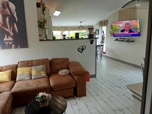 a living room with a couch and a flat screen tv at Au petit bonheur chez l'habitant in Ferques