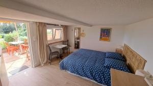 a bedroom with a blue bed and a balcony at L'Alizé du Levant in Île du Levant
