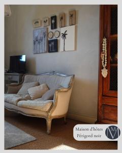 a living room with a couch and pictures on the wall at MAISON DE MARQUAY-MAISON D'HOTES in Marquay