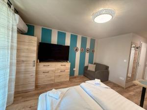 a bedroom with a bed and a flat screen tv at Nautica Stúdió by HelloBalatonlelle in Balatonlelle
