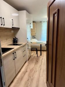 a kitchen with white cabinets and a sink and a table at Nautica Stúdió by HelloBalatonlelle in Balatonlelle