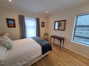 a bedroom with a bed and a table and a window at 5 Ysterklip Close, Hermanus in Hermanus