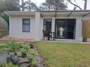 a small white house with a table in a yard at 5 Ysterklip Close, Hermanus in Hermanus