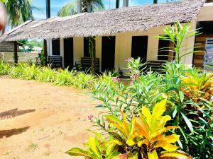 a small house with a thatched roof and some plants at TJ JANSE guest inn in Trincomalee