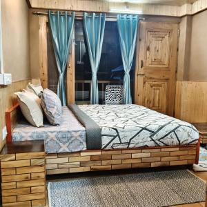 a bed in a room with blue curtains at The Morchella House Tirthan Valley in Gushaini