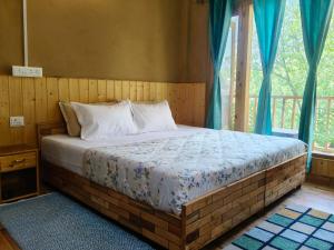 a bedroom with a large bed with blue curtains at The Morchella House Tirthan Valley in Gushaini