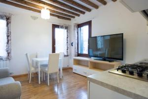 a kitchen and living room with a table and a television at Central Murano House in Murano